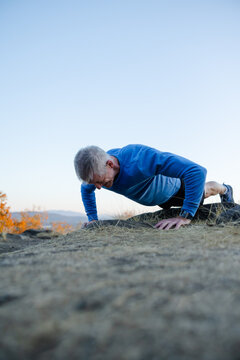 Man Doing Burpees Or Push-ups In Nature On A Hill.