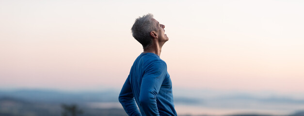 Tired runner man on top of hill after summiting.