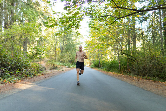 Fit man running hard on road in autumn or fall. 