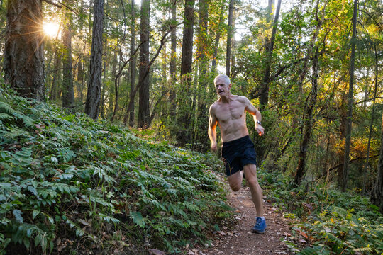 Man training and running on trails in the forest.