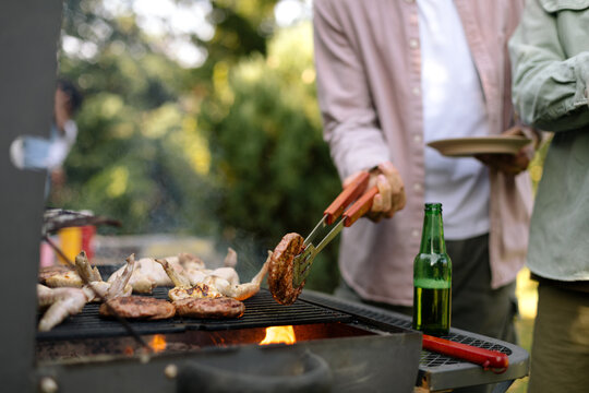 Man Grilling Burgers And Chicken Wings 