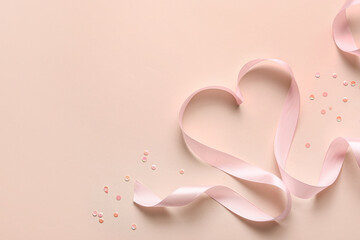 Pink ribbon with hearts on beige background. Valentine's Day celebration