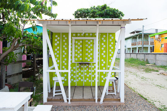 Green enclosed wooden store with white dots and white benches 