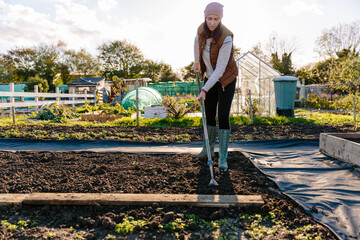 Woman working on an allotment garden in autumn