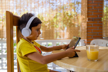 Kid in headphones using tablet in porch