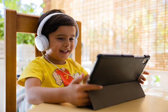 Smiling boy in headphones using tablet at home