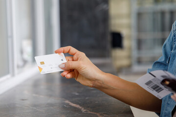 Close-up of woman holding ATM card while buying ticket at counter