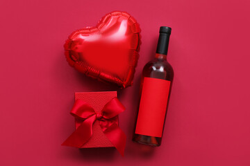 Bottle of wine, balloon and gift box on color background. Valentine's Day celebration
