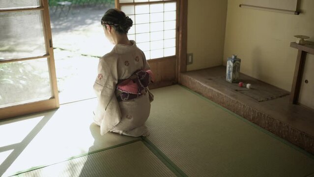 和室に正座して丁寧にお辞儀をする着物姿の女性