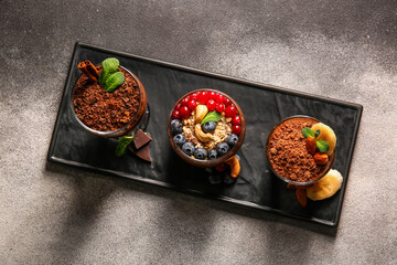 Board with glasses of various chocolate pudding on black and white table