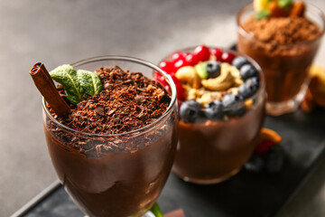 Board with glasses of various chocolate pudding on black and white table