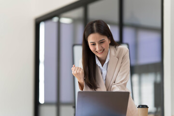 Pretty Asian businesswoman sitting on a laptop And the work came out successfully and the goal was achieved, happy and satisfied with her.