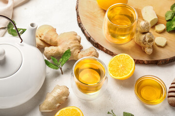 Composition with teapot, cup of tea, ginger, honey and lemon on light background