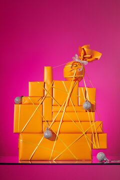 Stack of gifts with christmas balls on a pink background. Still life