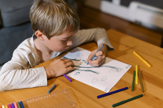 Little boy drawing at a wooden table with felt tip pens - Powered by Adobe