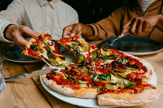 Anonymous Friends sharing delicious vegetarian pizza in restaurant 