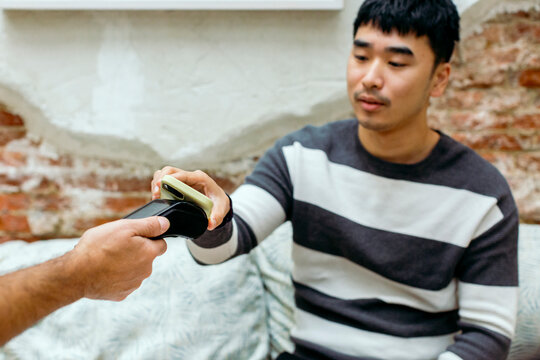 Man in cafe paying the check with mobile phone