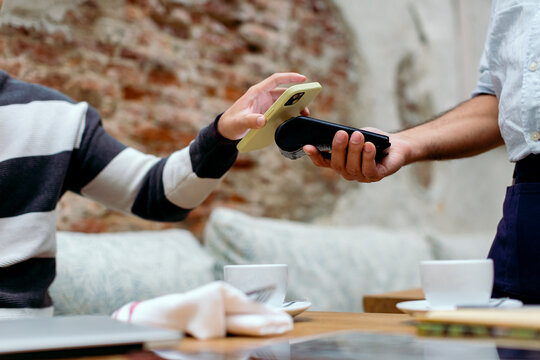 Anonymous hands paying restaurant check with smart phone