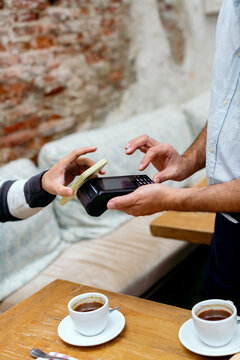 Anonymous hands paying the bill of cafeteria with mobile phone