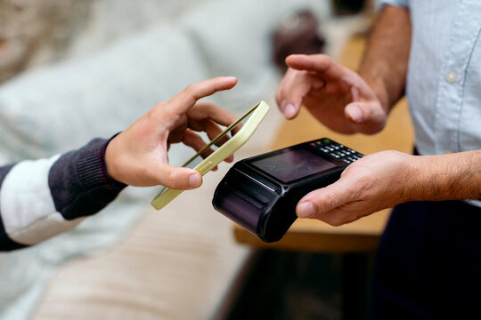 Anonymous hands paying the bill of cafeteria with mobile phone