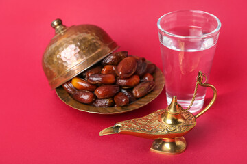 Aladdin lamp, dates and glass of water for Ramadan on red background