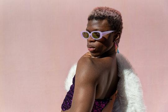 Transgender woman with sequined suit, white coat and sunglasses