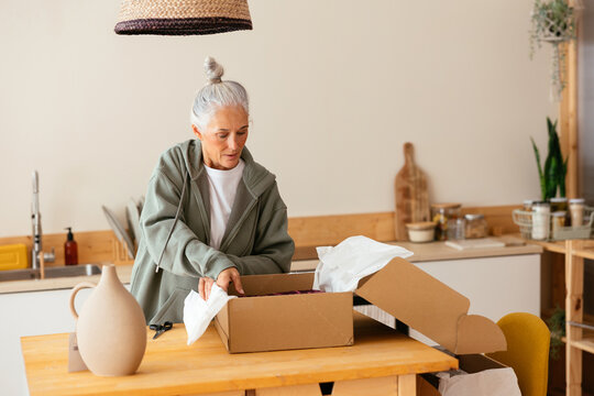 Mature woman unpacking order in kitchen