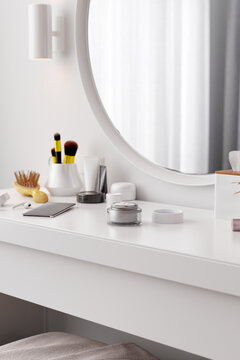 Cream, cosmetics, phone on dressing table. Interior shot.