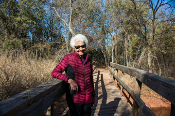 Naklejka na ściany i meble Active Senior on a nature trail in the woods crossing over a wooden pedestrian bridge located in Abilene State Park Texas