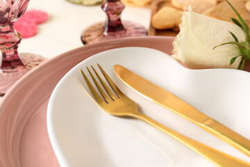 Heart shaped plate with golden cutlery, closeup. Valentine's Day celebration