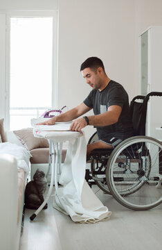 A man in a wheelchair strokes the curtains at home