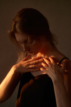 Young woman touching sunlit collarbones