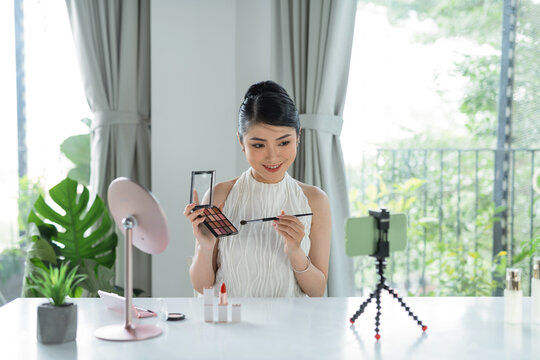 A beautiful Asian woman blogger shows how to make up and use cosmetics