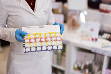 pharmacist woman putting pills into pill box