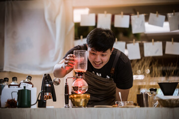 Professional coffee maker - Barista using coffee siphon brewing hot espresso at coffee shop coffee brewing syphon alternative method. Startup Business Concept.