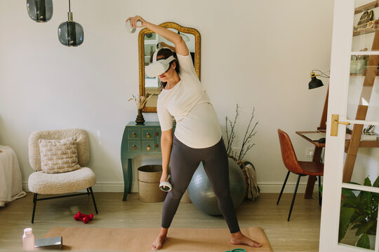 Pregnant woman doing yoga with a VR headset