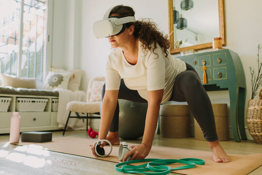 Pregnant woman using VR headset for practicing yoga