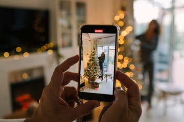 Man recording a video of his pregnant wife with the Christmas tree