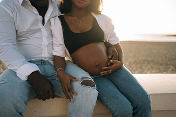 Crop couple resting on bench at beach