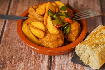 portion of meatballs with french fries in an earthenware dish