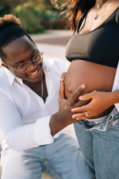 Happy man touching belly of wife in park