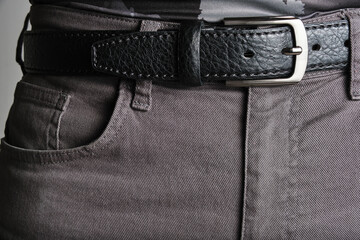 Buttoned black, male leather belt worn on jeans.