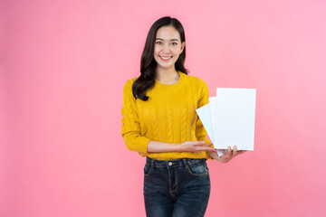 long haired female student Dressed in a yellow shirt, formal jeans, in her hand presents a white book. happy smile on the pink background studio High school university college education.