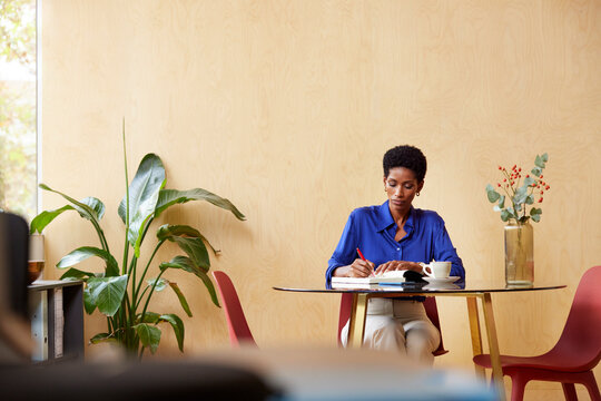 Black manager taking note of strategy in copybook