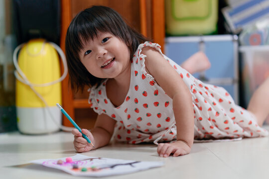 Adorable little child draws on paper with pencil