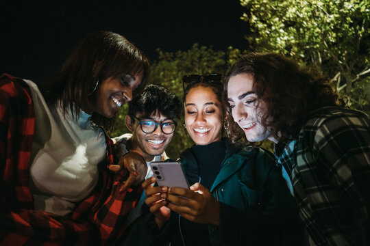 Cheerful diverse s using smartphone at night