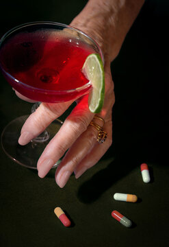 Woman Holds Alcoholic Beverage Next to Pills