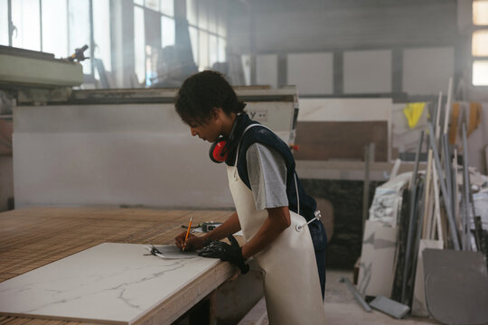 Craftswoman making notes in marble workshop