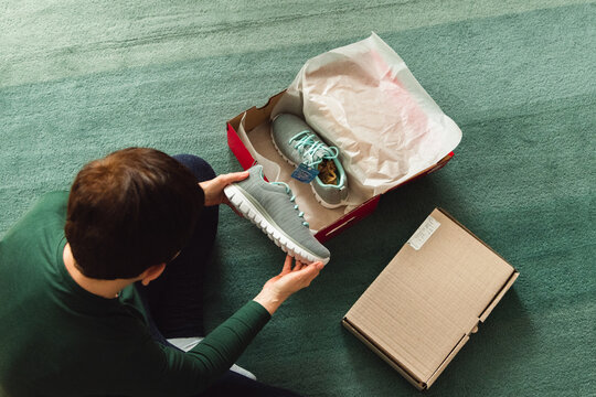 Middle-aged adult woman opening shoes delivery box