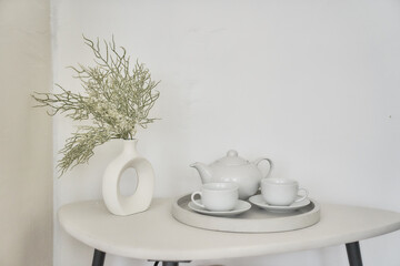 A minimalistic composition for a festive breakfast with beautiful white dishes, a bouquet of dried flowers in a vase on a light background. With a place to copy. High quality photo